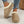 Vrouw draagt beige suède pantoffels met witte voering, gecombineerd met gescheurde jeans. Comfortabele wintermode, trendy damespantoffels.