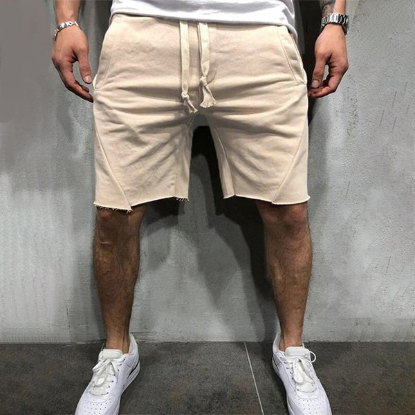 Beige herenshorts van katoen met rafelige zoom, gedragen door model. Comfortabele pasvorm, casual stijl, ideaal voor zomermode en vrijetijdskleding.