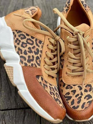 Luipaardprint sneakers op houten achtergrond, trendy damesmode, casual schoenen met dikke zolen en veters, stijlvol en comfortabel ontwerp.