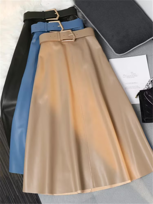 Drie leren rokken met riemen in zwart, blauw en beige op een grijze bank. Stijlvolle damesmode, trendy kleuren, elegante uitstraling.