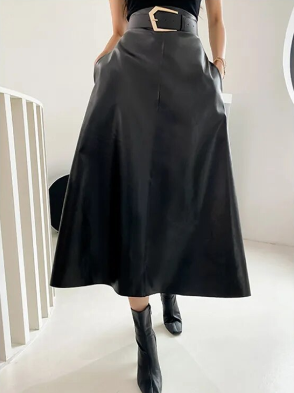 Zwarte leren midi-rok met hoge taille en brede riem, gecombineerd met zwarte enkellaarsjes. Stijlvolle damesmode, perfect voor herfst- en winteroutfits.