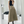 Vrouw in zwarte top en beige midi-rok met riem, poseert voor spiegel. Modieuze outfit, trendy kleding, stijlvolle damesmode, herfstlook.