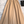 Beige leren midi-rok op een witte pluchen achtergrond, met een geplooid ontwerp en een brede tailleband. Stijlvolle damesmode, elegant en trendy.