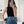 Vrouw in zwarte mouwloze top en blauwe leren rok met brede riem, maakt selfie in moderne minimalistische kamer. Fashion, mode, trendy outfit.