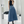 Vrouw in blauwe midi-rok met riem en zwarte top, poseert voor spiegel. Modieuze outfit, trendy kleding, stijlvolle damesmode, moderne look.