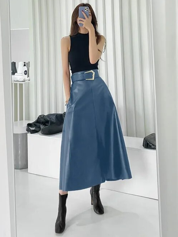 Vrouw in blauwe midi-rok met riem en zwarte top, poseert voor spiegel. Modieuze outfit, trendy kleding, stijlvolle damesmode, moderne look.