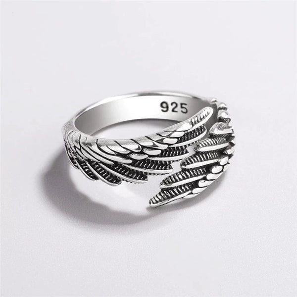 Zilveren ring met vleugelontwerp, gegraveerd met "925" voor sterling zilver, op een witte achtergrond. Perfecte sieraden voor dagelijks gebruik.