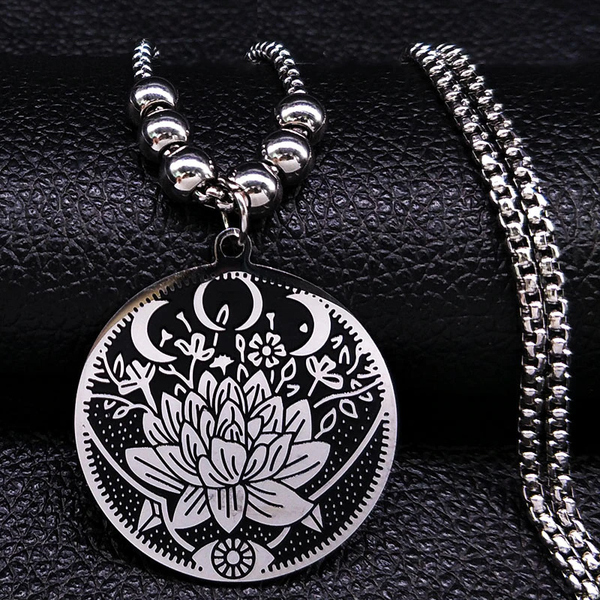 Zilveren ketting met ronde hanger, lotusgravure en maansymbolen, op zwarte achtergrond. Stijlvolle sieraden, bohemian design, spirituele betekenis.