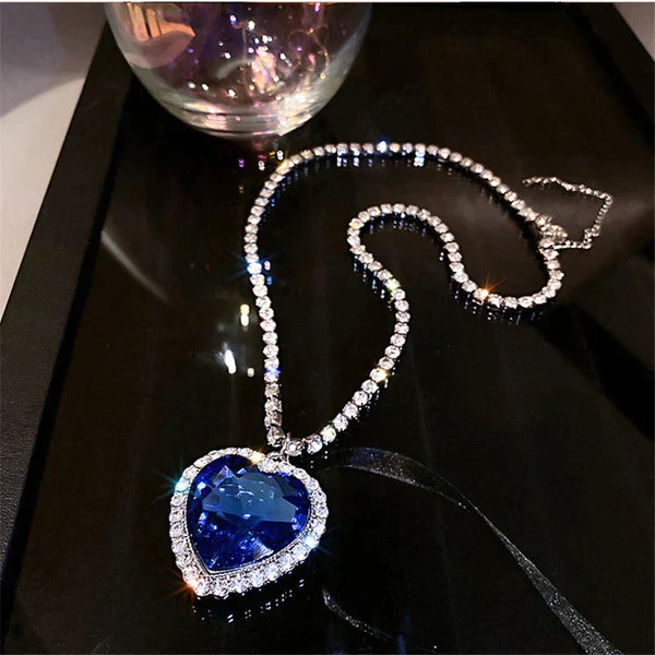 Hartvormige blauwe saffier hanger ketting met diamanten, elegant gepresenteerd op een zwarte achtergrond. Luxe sieraden, glinsterende edelstenen.