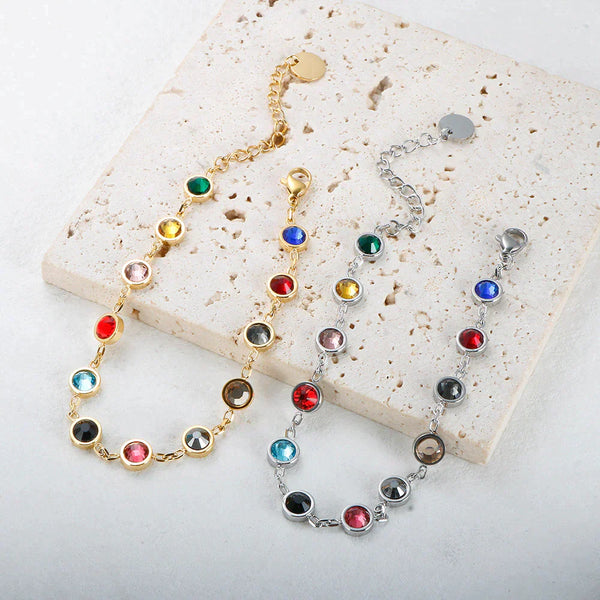 Vier armbanden met kleurrijke edelstenen op een beige achtergrond. Gouden en zilveren schakels, perfect voor sieradenliefhebbers en modeaccessoires.
