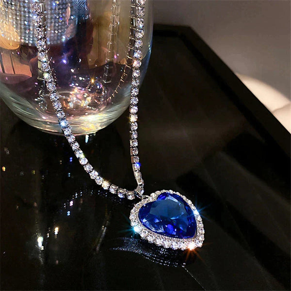 Hartvormige blauwe saffier hanger met diamanten op een zilveren ketting, glinsterend op een zwarte achtergrond. Luxe sieraden, elegante halsketting.