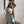 Vrouw in geruite blazer en gescheurde jeans loopt op straat. Modieuze herfstoutfit, casual stijl, stedelijke achtergrond, trendy dameskleding.