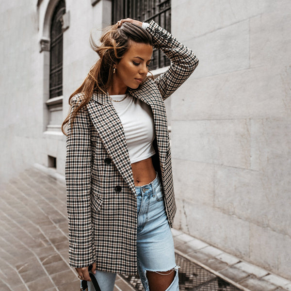 Vrouw in geruite blazer en gescheurde jeans loopt op straat. Modieuze herfstoutfit, casual stijl, stedelijke achtergrond, trendy dameskleding.