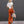 Vrouw in witte gebreide trui en oranje flared broek met beige tas, poseert voor grijze achtergrond. Modieuze herfstoutfit, trendy dameskleding.