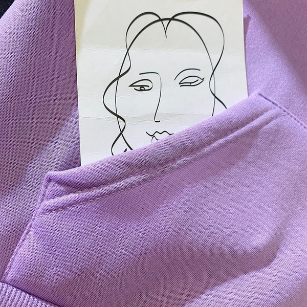 Lila trui met schets van gezicht in zak, minimalistische kunst, moderne mode, zachte stof, trendy kleding, artistieke stijl.