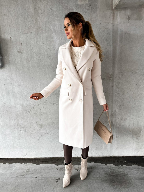 Vrouw in elegante, lange, witte wollen jas met dubbele rij knopen, herfst-winter mode 2022, gecombineerd met beige handtas en laarzen.