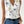 Vrouw draagt witte mouwloze blouse met bloemenprint, V-hals en blauwe jeans. Zomer casual mode 2023, trendy dameskleding.