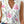 Vrouw draagt witte mouwloze blouse met V-hals en kleurrijke bloemenprint, zomer 2023 mode, casual stijl, perfect voor warme dagen.