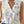 Vrouw draagt witte mouwloze blouse met bloemenprint en V-hals, gecombineerd met blauwe jeans. Zomer casual mode 2023, trendy dameskleding.
