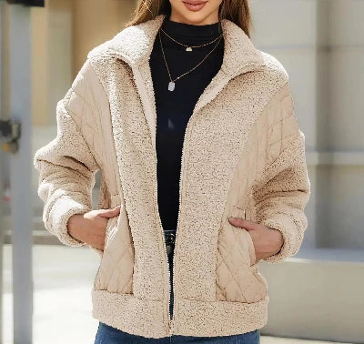Vrouw in beige teddyjas met rits, zwarte coltrui en spijkerbroek. Modieuze winterkleding, casual stijl, comfortabele warme jas.