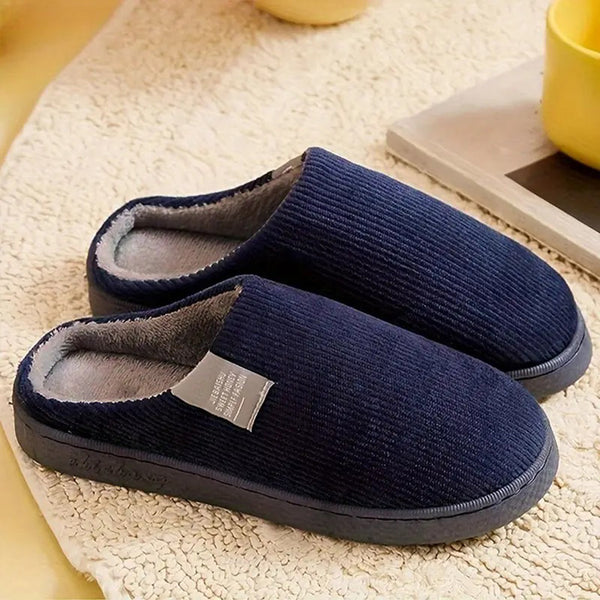 Donkerblauwe pantoffels met zachte voering op beige tapijt, comfortabele winterse huisschoenen, warme sloffen voor heren en dames, gezellig thuis.