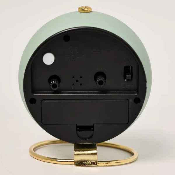 Achterkant van een minimalistische, Scandinavische elektronische wekker met groene behuizing en gouden standaard. Stille en kindvriendelijke klok.