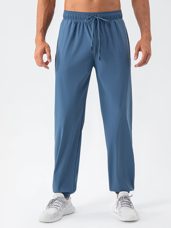 Blauwe sportbroek voor heren, gemaakt van ademend materiaal, met elastische tailleband en trekkoord. Ideaal voor fitness en hardlopen.