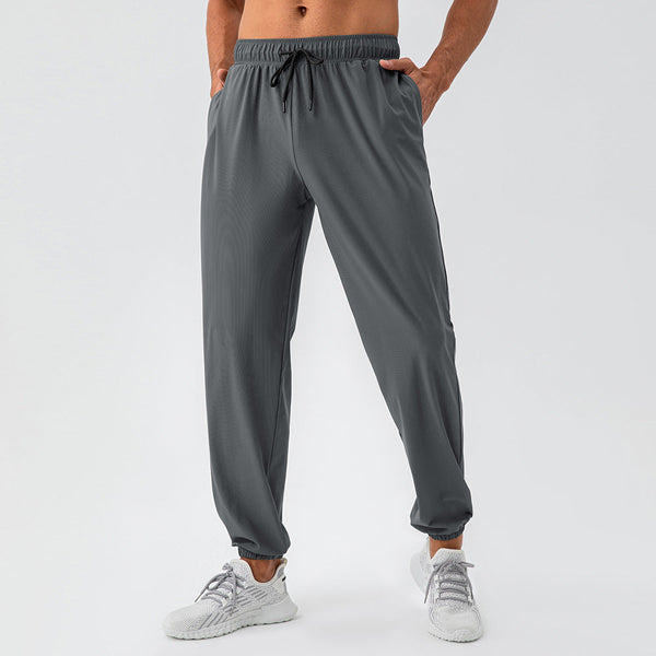 Grijze sportbroek voor heren, gemaakt van ademend materiaal met elastische tailleband en trekkoord. Perfect voor fitness en casual dragen.