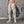 Man in beige joggers en sneakers poseert voor een muur met graffiti. Sportieve kleding, casual stijl, fitnessmode, comfortabele joggingbroek.