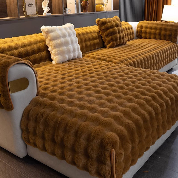 Bruine pluche bankhoes met gewatteerd patroon, inclusief bijpassende kussens, in moderne woonkamer. Comfortabele en stijlvolle interieurdecoratie.