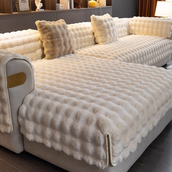 Luxe witte pluchen bankhoes met textuur, inclusief bijpassende kussens, in een moderne woonkamer. Perfect voor interieurdecoratie en comfort.