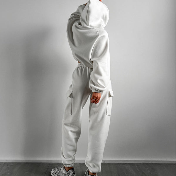 Persoon in witte joggingbroek en hoodie, casual sportkleding, comfortabele loungewear, mode voor thuis, minimalistisch design, grijze achtergrond.