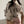 Vrouw in beige wollen jas en gebreide jurk, zittend op rieten stoel, minimalistische mode, herfst winter outfit, stijlvolle dameskleding.