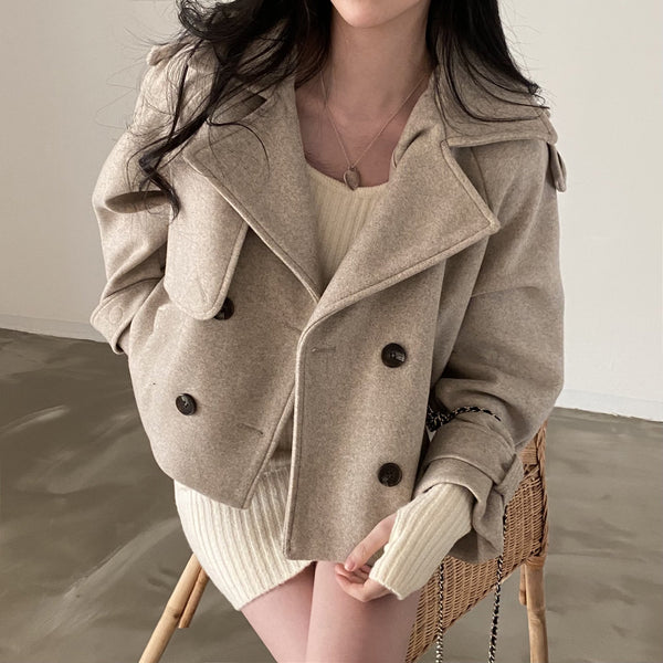 Vrouw in beige wollen jas en gebreide jurk, zittend op een stoel. Modieuze herfstkleding, stijlvolle damesmode, comfortabele en warme outfit.