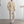 Man in crèmekleurige outfit met geribbelde jas, beige trui en broek, draagt zwart-wit geblokte schoenen. Moderne minimalistische mode.