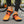 Oranje hardloopschoenen met zwarte zool en veters, gedragen door persoon op asfaltweg. Ideaal voor sport, fitness en outdoor activiteiten.