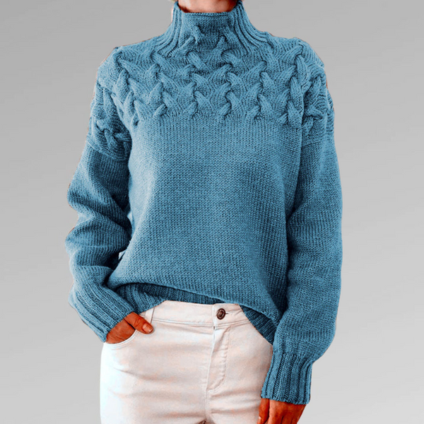 Blauwe kabeltrui dames, hoge hals, gebreid patroon, casual wintermode, comfortabele warme kleding, stijlvolle outfit, grijze achtergrond.