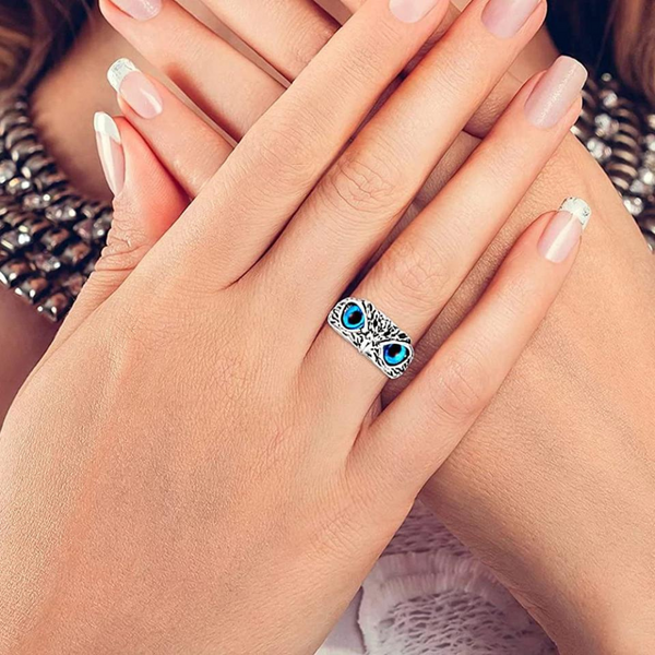 Twee handen met een zilveren ring met blauwe stenen, gedragen door een vrouw met verzorgde nagels. Elegante sieraden, modeaccessoire.