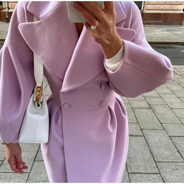 Vrouw in stijlvolle lila jas met witte handtas, straatmode, herfstkleding, elegante damesmode, trendy pastelkleuren, stedelijke achtergrond.