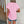 Vrouw in roze geperforeerd T-shirt en denim shorts voor houten deur. Zomermode, casual outfit, trendy kledingstijl, comfortabele dameskleding.