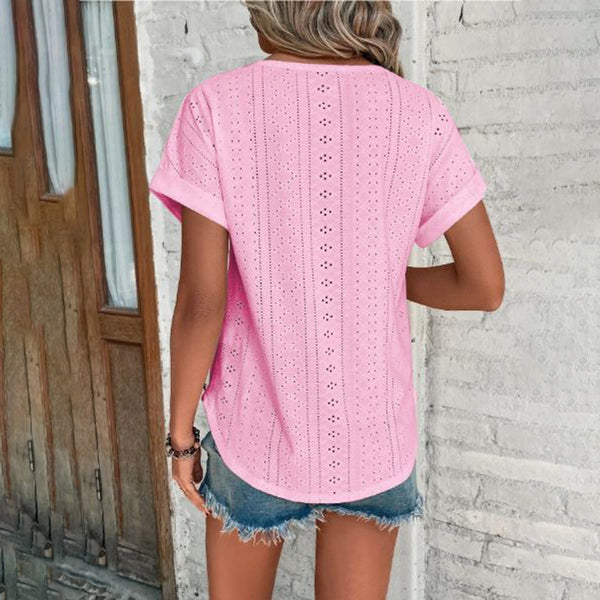 Vrouw in roze geperforeerd T-shirt en denim shorts voor houten deur. Zomermode, casual outfit, trendy kledingstijl, comfortabele dameskleding.