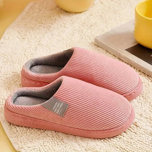 Roze pluchen pantoffels op beige tapijt, comfortabele winterse huisschoenen, warme voering, perfect voor binnengebruik, naast gele mok.