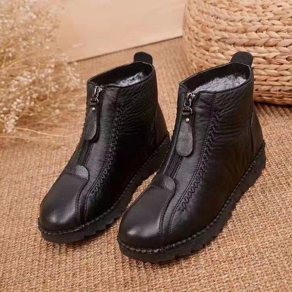Zwarte leren enkellaarzen met ritssluiting, warme voering en stevige zool, geplaatst op een rustieke jute achtergrond. Perfect voor wintermode.