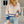 Vrouw in beige en blauwe trui met ritssluiting, casual stijl, gecombineerd met lichtblauwe jeans. Perfect voor herfstmode en streetwear trends.