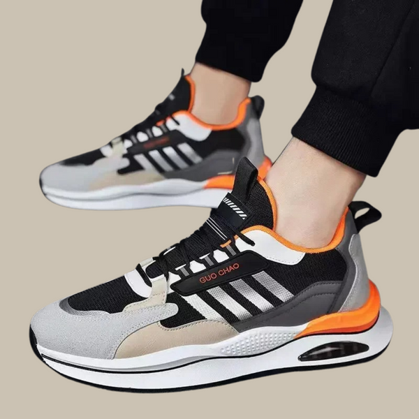 Moderne sportschoenen met zwart-wit design, oranje accenten en luchtkussenzool. Ideaal voor hardlopen en casual gebruik. Comfortabele sneakers.