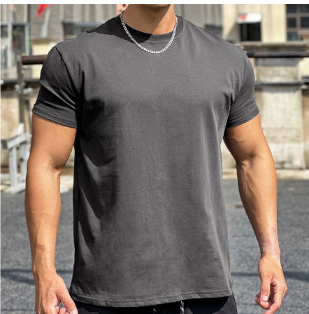 Man in grijs T-shirt met korte mouwen en zilveren ketting, gespierde armen, buiten gefotografeerd. Casual herenkleding, fitnessmode.