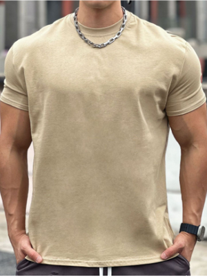 Man in beige T-shirt met ketting en horloge, buiten op stedelijke achtergrond. Casual herenkleding, mode, zomeroutfit.