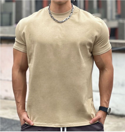 Man in beige T-shirt met ketting en horloge, buiten op stedelijke achtergrond. Casual herenkleding, mode, zomeroutfit.