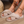 Vrouw draagt beige pluche pantoffels met gekruiste banden op houten vloer. Comfortabele dames slippers, trendy en warm voor binnengebruik.