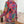 Vrouw in kleurrijke patchwork jas met etnische patronen, staand bij een cactus. Bohemian mode, opvallende kleuren, unieke stijl.